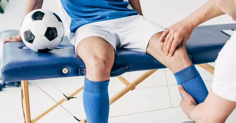 Sports chiropractor treating an athlete's knee injury beside a soccer ball